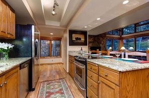 A kitchen with wooden cabinets, granite countertops, a stove, and a refrigerator. - Abode on Stonebridge, hot tub, Deer Valley & Main Street, bunkroom (Park City)