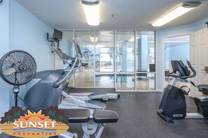 Une salle de sport équipée de tapis de course, d’un vélo d’appartement et d’un ventilateur.