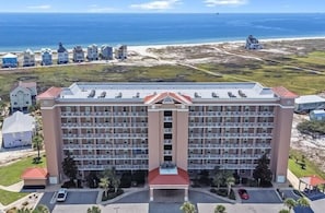 A large hotel with multiple floors, a central courtyard, and a view of the beach and ocean.