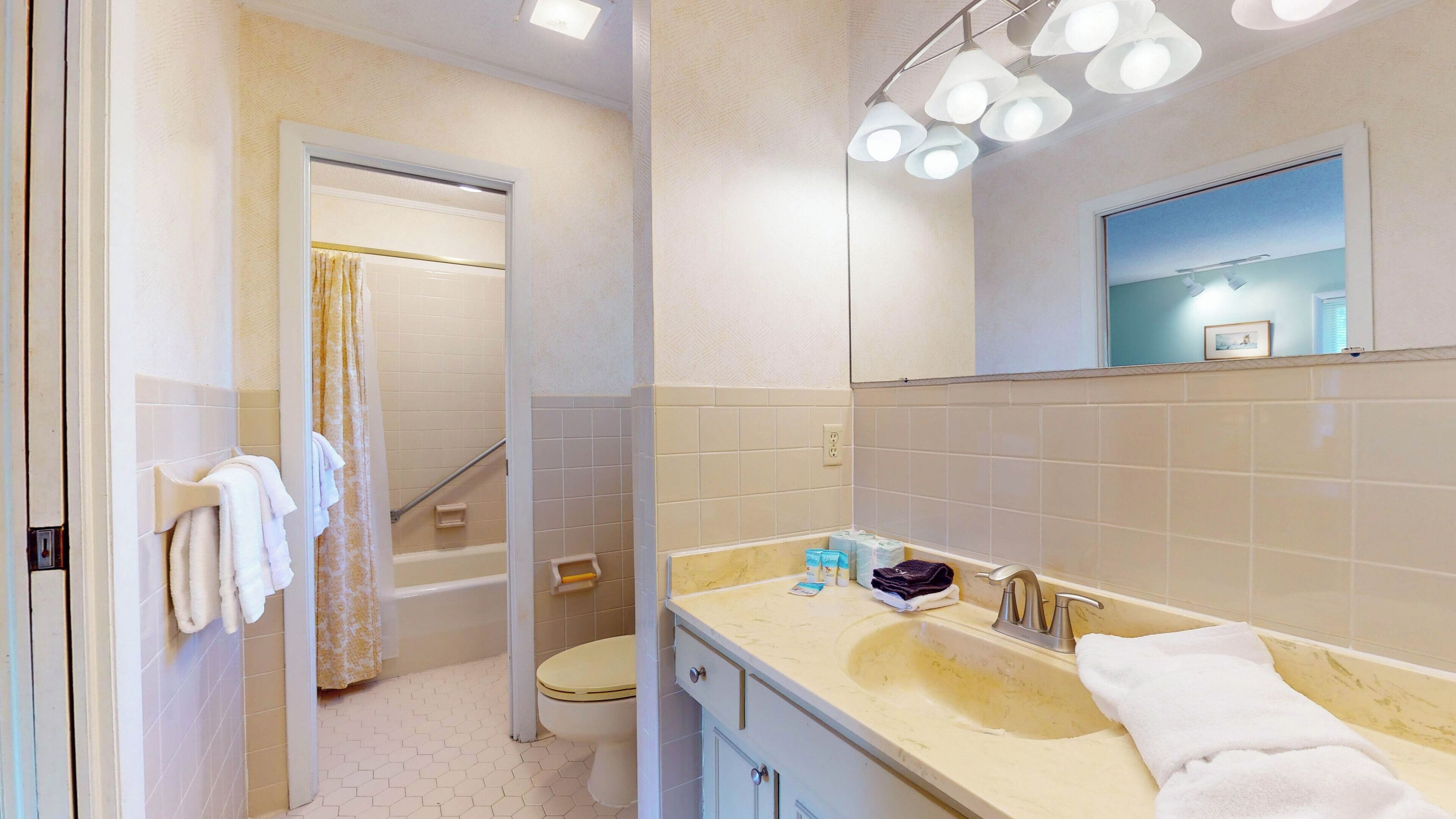 A bathroom with a bathtub, a sink with a mirror, and a toilet.
