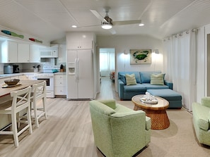 Relax in a spacious living area with a sofa set and armchair, and enjoy a meal at the dining table with kitchen and refrigerator.