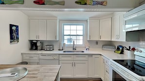 Una cocina con armarios blancos, una ventana, un lavabo, un tostador y una estufa.