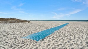 Uma praia arenosa com um tapete azul estendido ao centro.