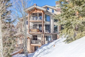 A multi-story building with balconies, a staircase, and a snowy landscape.