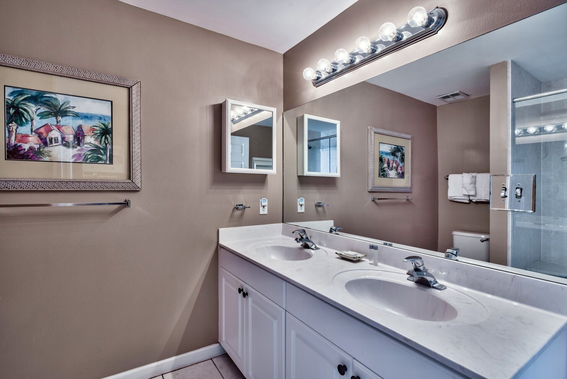 A bathroom with two sinks, a large mirror, and a lighted vanity.