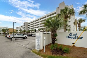 A parking lot with a white building labeled 'Surf Dweller' and palm trees.