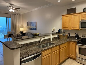 A modern kitchen with granite countertops, wooden cabinets, a built-in dishwasher, and an oven.