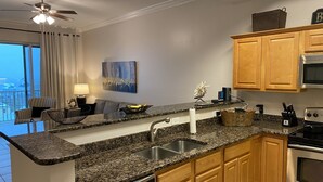 Eine moderne Küche mit Granit-Arbeitsplatten, Holzschränken, einem eingebauten Geschirrspüler und einem Backofen.