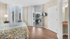 Ein Hotelzimmer mit Bett, Fernseher, Tür und Blick nach draußen.