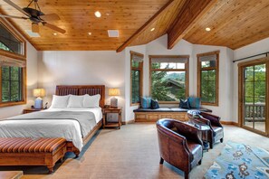 Un dormitorio espacioso con una cama grande, techo de madera y amplias ventanas con vistas al exterior.