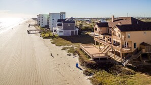A beachfront property with multiple-story buildings, a wooden deck, and a beach view. - Paradise At Last | Beachfront Escape w/ Direct Beach Access (Galveston)