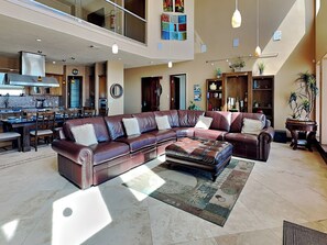 A spacious living area with a large L-shaped sectional sofa, a dining table with chairs, and a kitchen in the background. - Paradise At Last | Beachfront Escape w/ Direct Beach Access (Galveston)