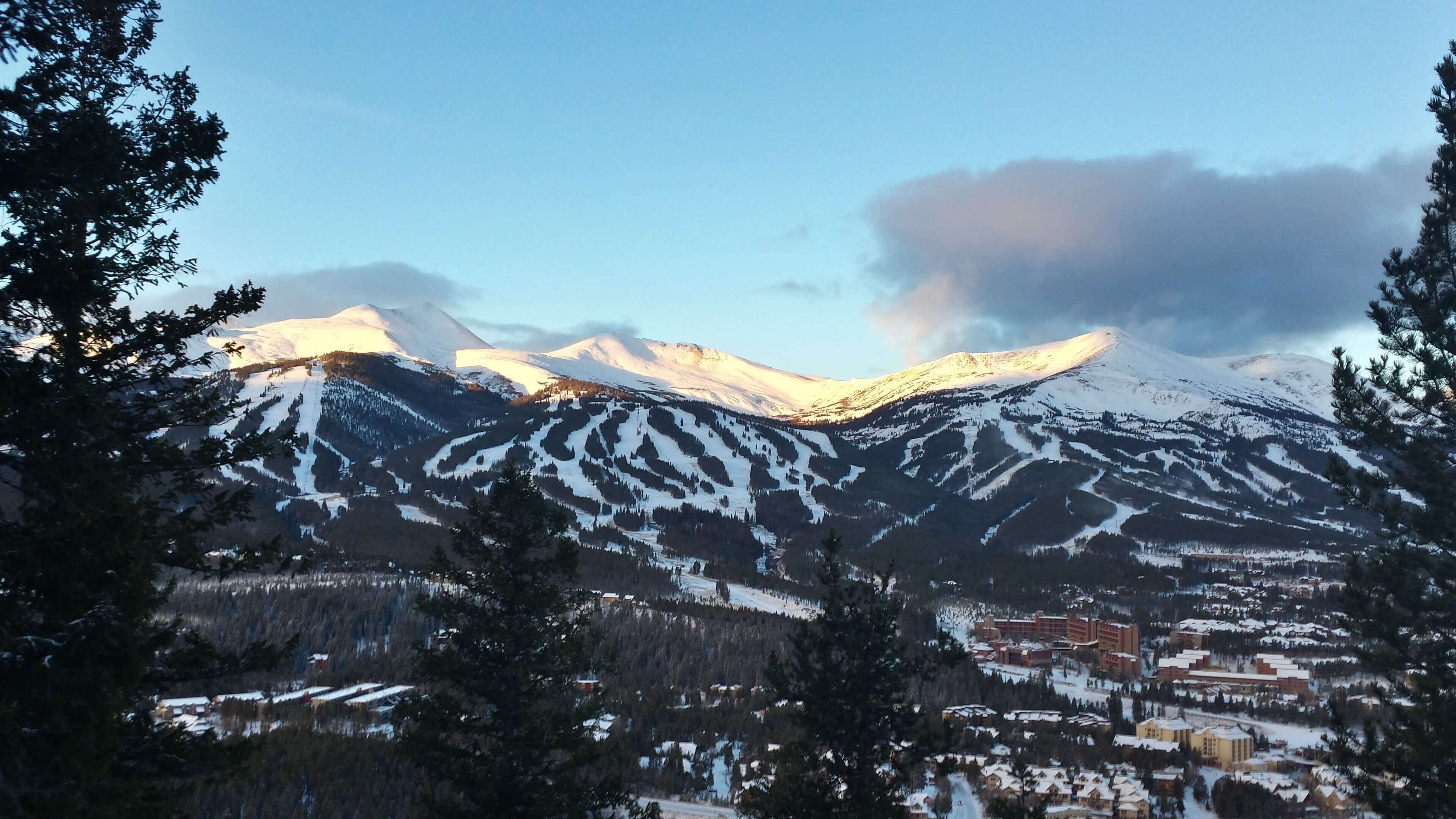 A mountain range with snow-covered peaks and a town at the base.