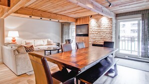 A modern living room with a wooden ceiling, a large dining table, and a sofa set. - Elegant Downtown Chateau | Walk to Shop, Ski & Dine (Aspen)