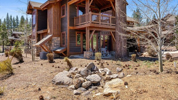 Une cabane en bois dotée d’un balcon, d’un escalier en pierre et d’un espace patio.