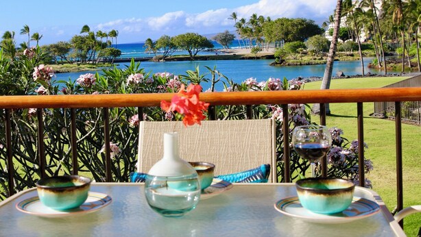 Une table ornée d’un vase et de deux bols, offrant une vue panoramique sur une plage et l’océan.