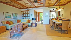 A spacious living room with a sofa, chairs, a dining area with a table and chairs, and a ceiling fan.