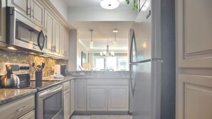 Una cocina moderna con armarios blancos, electrodomésticos de acero inoxidable y encimera de granito.