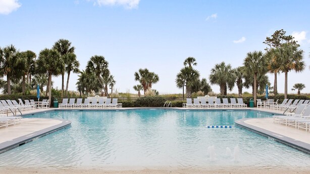 Una piscina con sillas de descanso y palmeras.