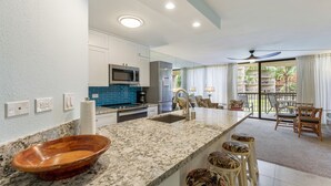 A modern kitchen with a large island, built-in appliances, and a view to a dining area with outdoor seating. - King size bed!   On the ocean front property (Kihei)
