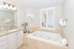 A modern bathroom with a large bathtub, a double sink vanity, and a window with white shutters. - Modern Condo w/ 2 Beachfront Pools & Close Dining in Central Destin! 💙🌺🏖 (Destin)