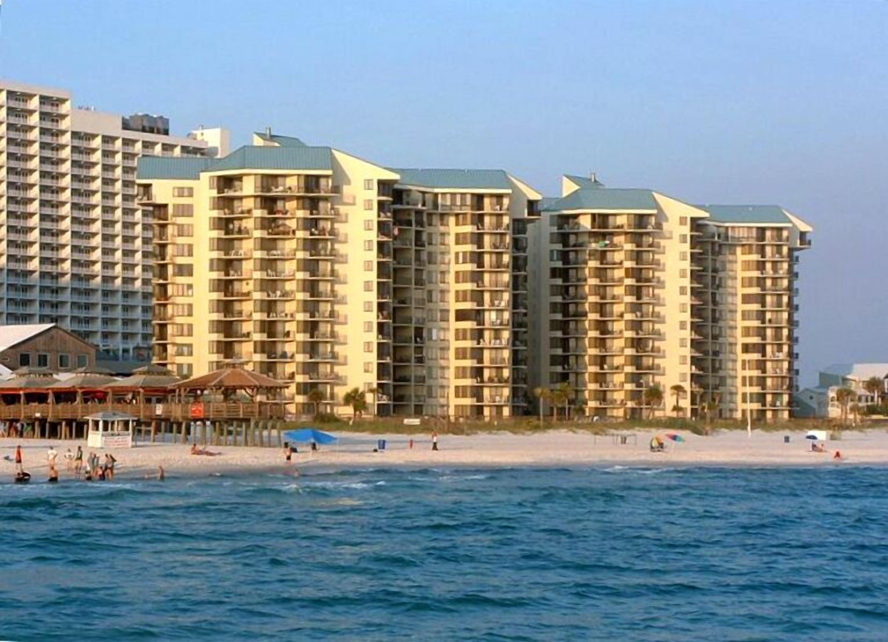 A beachfront hotel with multiple high-rise buildings, a sandy beach, and the ocean.