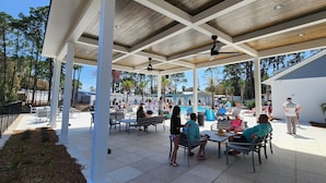 Ein Außenbereich mit Terrasse, Pool, Sitzgelegenheiten und überdachtem Bereich.