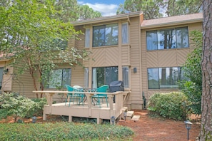 A two-story building with a covered patio area featuring outdoor furniture.