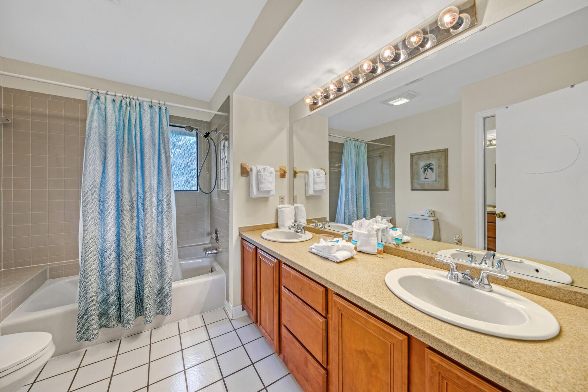A bathroom with a bathtub, a shower, two sinks, and a large mirror with lights.