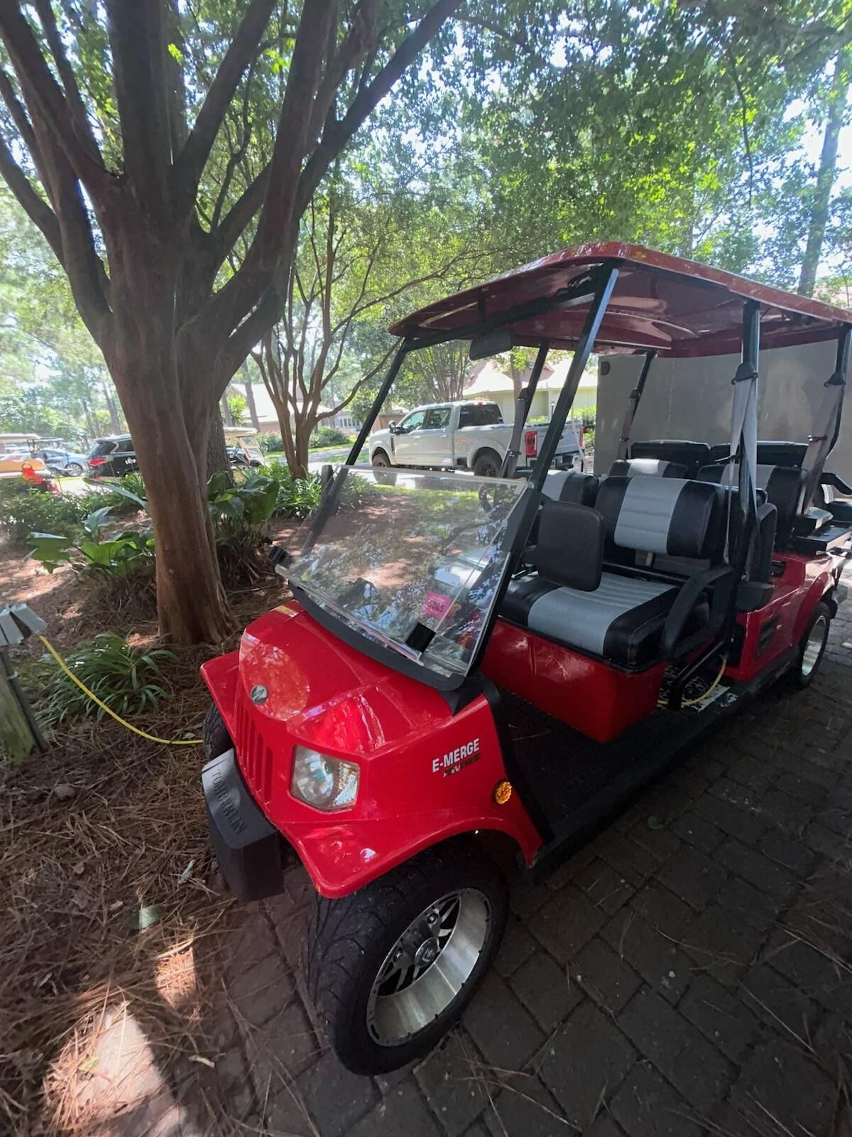 A red golf cart parked near a tree.