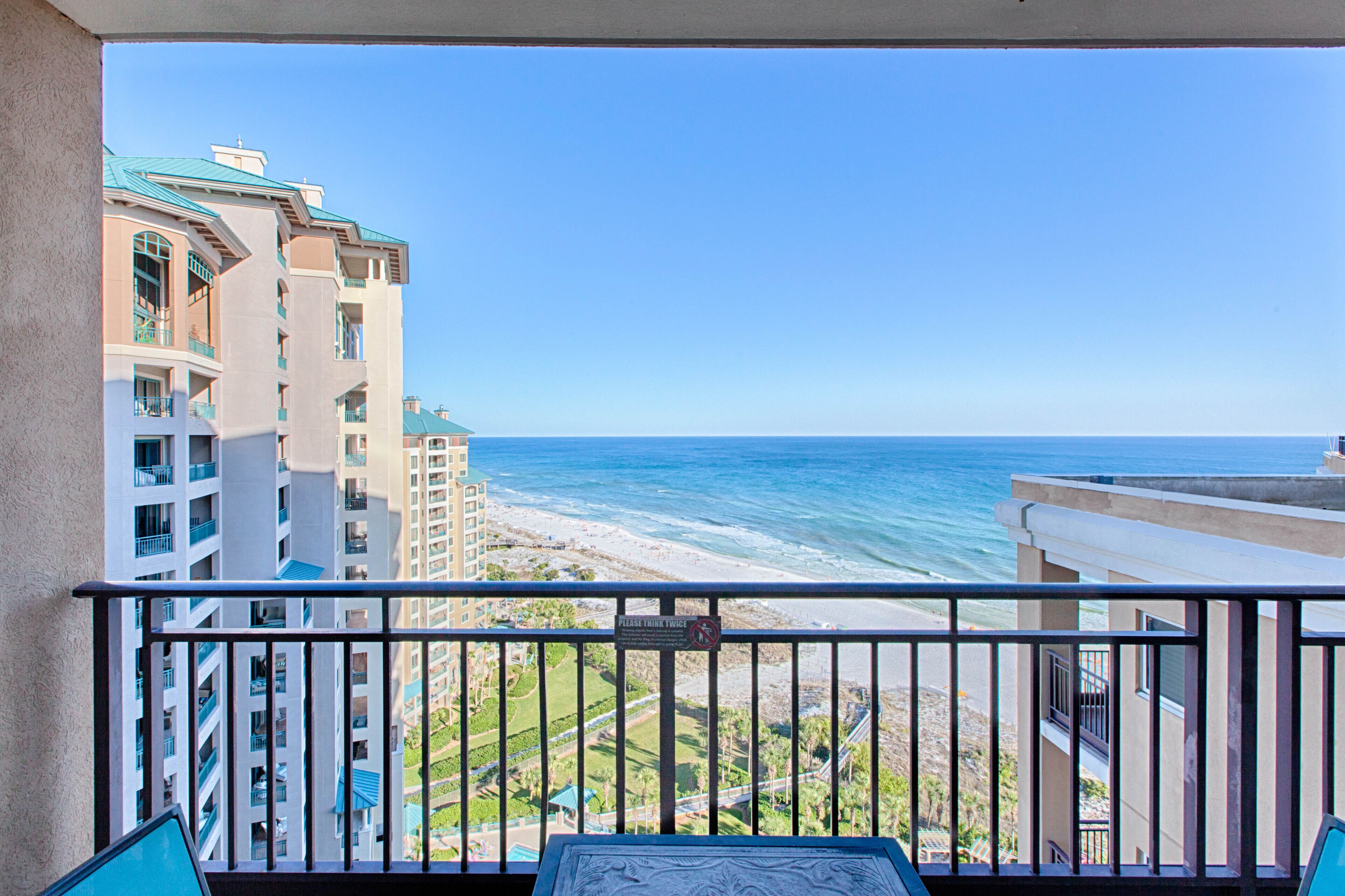 A balcony with a view of the ocean and adjacent buildings.