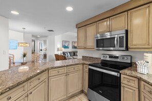 A kitchen with granite countertops, wooden cabinets, a built-in microwave, and an oven.