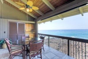 Relax in this serene outdoor space with a glass table and wicker chairs, overlooking the ocean from the adjacent balcony.