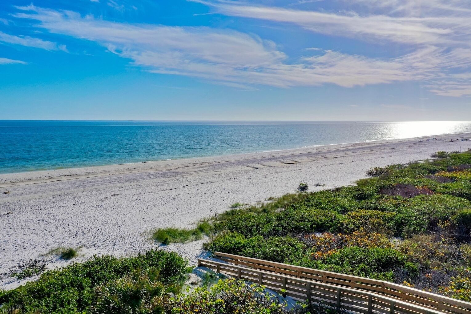 A beach with a wooden walkway leading to the shore.