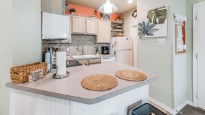 A kitchen with a central island, white cabinets, a microwave, a coffee maker, and a refrigerator.