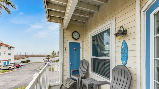 A porch with two Adirondack chairs, a blue door, and a clock.