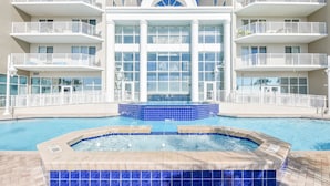 A hotel with a large indoor swimming pool, multiple balconies, and a central water feature.