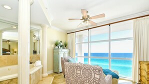 A spacious room with a large window, a ceiling fan, and a view of the ocean.