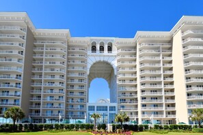 A multi-story hotel with a central archway, balconies, and a well-maintained garden. - Two-story penthouse w/two private balconies! Majestic Sun 1106A (Miramar Beach)