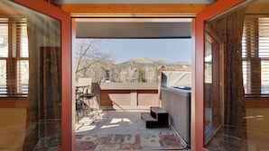 A view from a room with a sliding glass door leading to an outdoor patio with a hot tub, a table, and chairs. - Downtown Gem - Ski Resort Views, Private Hot Tub, Dog-Friendly MainD (Breckenridge)