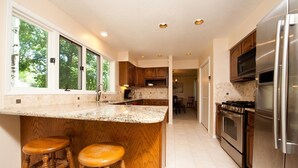Une cuisine moderne dotée d’un grand îlot central, d’appareils électroménagers en acier inoxydable et de tabourets de bar en bois.