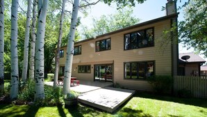 Une maison à deux étages avec un patio, entourée de bouleaux.