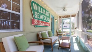 A cozy outdoor seating area with wooden furniture and a sign for Williams Seafood Restaurant. - Just Beachy | Pet Friendly, Pool, Fenced Yard! (Tybee Island)