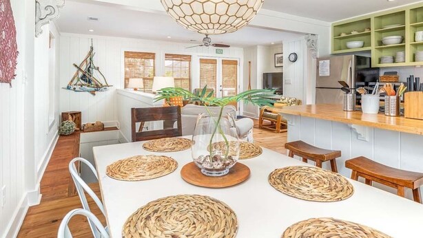 A modern kitchen with a central island, wooden flooring, and a hanging light fixture. - Just Beachy | Pet Friendly, Pool, Fenced Yard! (Tybee Island)