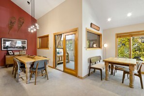 A dining area with wooden tables and chairs, a chandelier, and a large mirror. - Lulu City #4C Fresh Mountain Style Steps to Coonskin Lift Sleeps 7 (Telluride)
