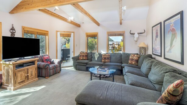 A spacious living room with a large flat-screen TV, a wooden entertainment unit, and a sofa set. - Spacious Condo in Telluride-Beautiful West Views! (Telluride)