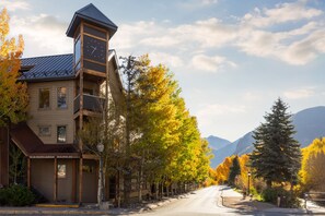 A building with a clock tower, a street lined with trees, and mountains in the background. - Lulu City #4C Fresh Mountain Style Steps to Coonskin Lift Sleeps 7 (Telluride)