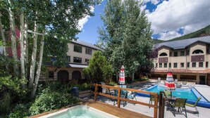 A pool area with a hot tub, lounge chairs, and umbrellas. - Spacious Condo in Telluride-Beautiful West Views! (Telluride)