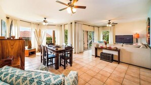 A spacious living area with a dining table, sofas, and a TV.