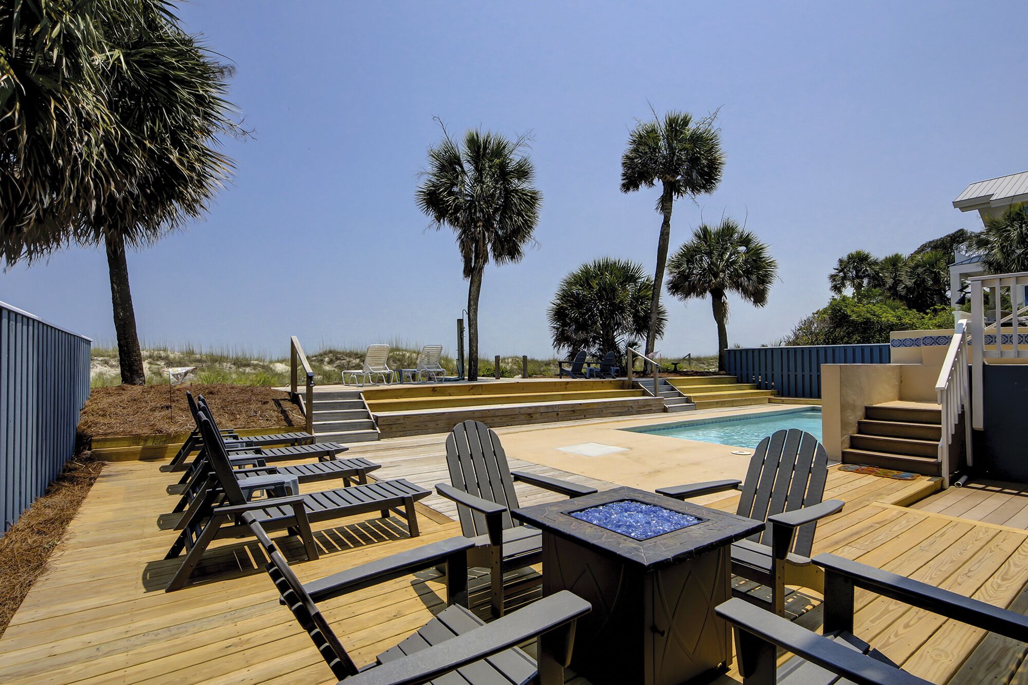 A poolside area with wooden deck, lounge chairs, and a hot tub.